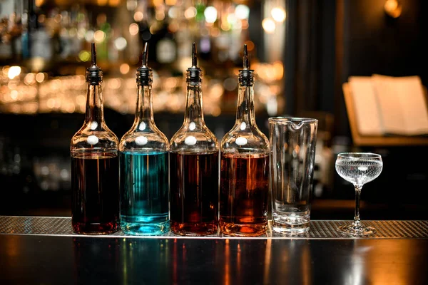 Varias botellas de diferentes colores con bebidas alcohólicas y dos vasos de pie en la barra . —  Fotos de Stock