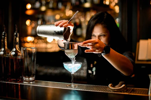 Barman verse le cocktail du shaker dans le verre à l'aide d'un tamis . — Photo