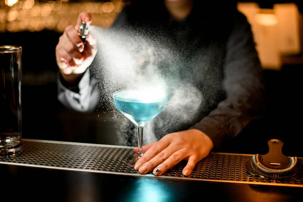 Γυναίκα μπάρμαν ψεκάζει σε μπλε κοκτέιλ σε ποτήρι στο μπαρ — Φωτογραφία Αρχείου