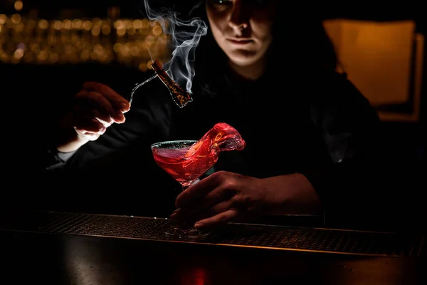 Barman chica sostiene fumar varita y vidrio con rojo salpicadura bebida . — Foto de Stock