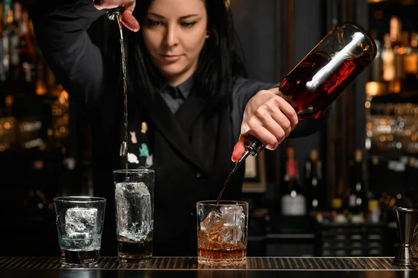 A csapos lány italos üvegeket tart, és a profi jéggel töltött üvegbe önti.. — Stock Fotó
