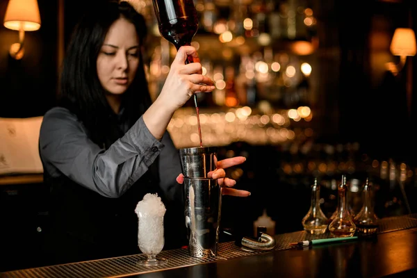 Mulher barman derrama bebida alcoólica de garrafa em shaker . — Fotografia de Stock