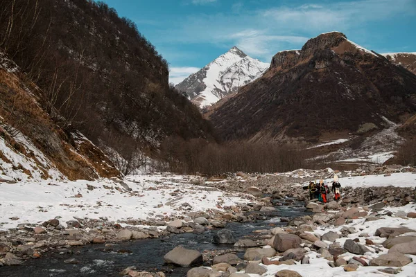 Grupo de viajeros con equipo de esquí paseos a lo largo del río de montaña . — Foto de Stock