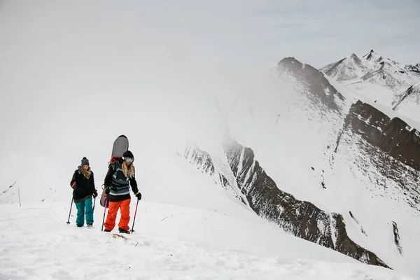 Duas mulheres com equipamento de esqui escalam a montanha para fazer freeride . — Fotografia de Stock