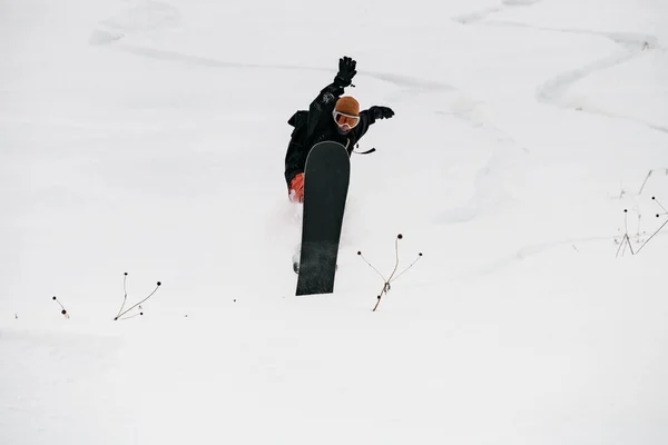 雪に覆われた丘の中腹を滑降した後の土地が飛ぶときにスノーボーダーの解放者のバランス — ストック写真