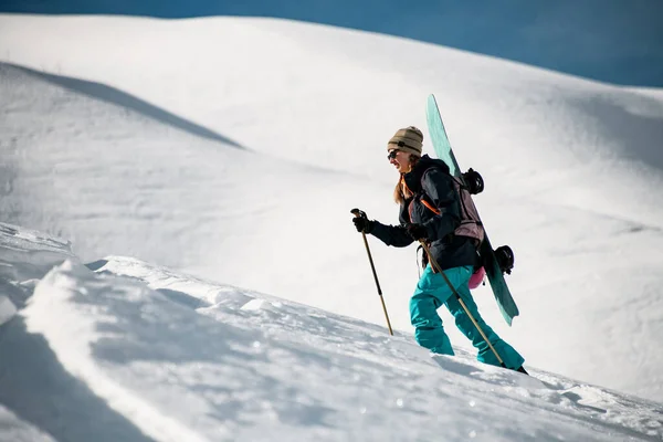 Женщина-путешественница поднимается на гору на сноуборде — стоковое фото