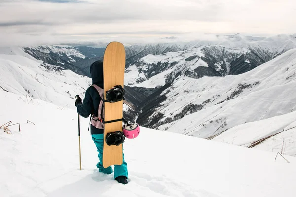 Turista feminino com snowboard e bengalas no topo da montanha — Fotografia de Stock