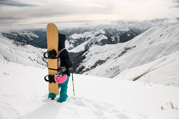 Γυναίκα πεζοπόρος με snowboard και μπαστούνια στην κορυφή του βουνού — Φωτογραφία Αρχείου