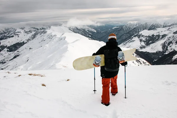 スノーボードのある男性観光客が山頂を歩く — ストック写真