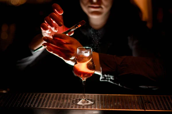 Junge brünette Frau dekoriert alkoholischen Cocktail mit farbigem Puder mit Pinsel. — Stockfoto