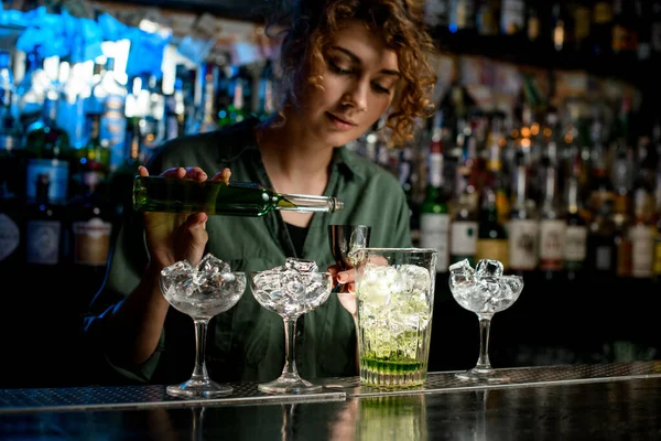 Mujer camarera comienza a verter líquido verde de la botella en vaso de precipitados . — Foto de Stock