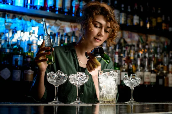 Jong vrouw barman schenkt groen drankje in groot glas gebruikt beker. — Stockfoto