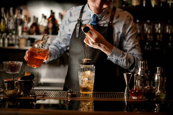 Barman profesional usando vaso de precipitados vierte bebida en vaso agitador —  Fotos de Stock