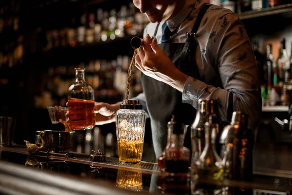 Barman pomocí kádinky pečlivě nalévá nápoj do skleněné třepačky — Stock fotografie