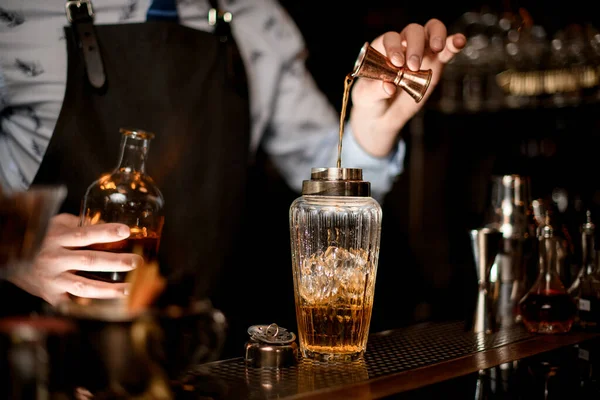 Cercanía camarero usando vaso de precipitados vierte bebida en vaso agitador —  Fotos de Stock