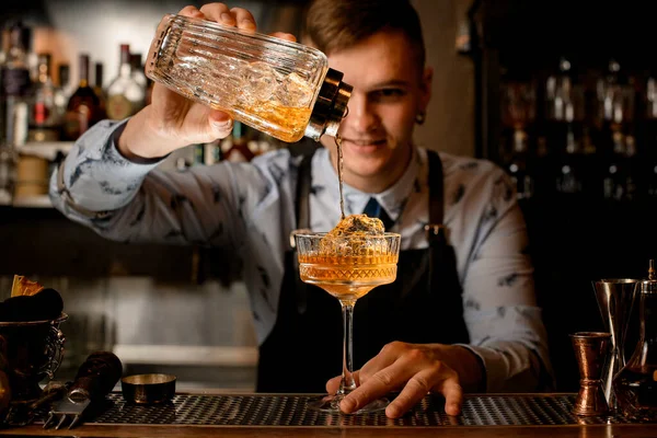 Barman joven vierte cóctel terminado de coctelera vidriosa en vidrio con hielo . —  Fotos de Stock