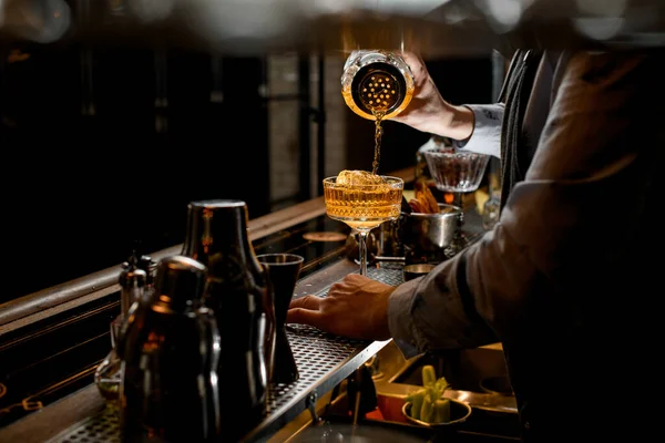 Profesjonalny barman starannie wlewa gotowy koktajl z shakera szklanego do szklanki z lodem. — Zdjęcie stockowe