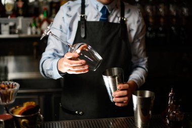 Barmen kokteyl yapmak için bardak ve sallama hazırlıyor..