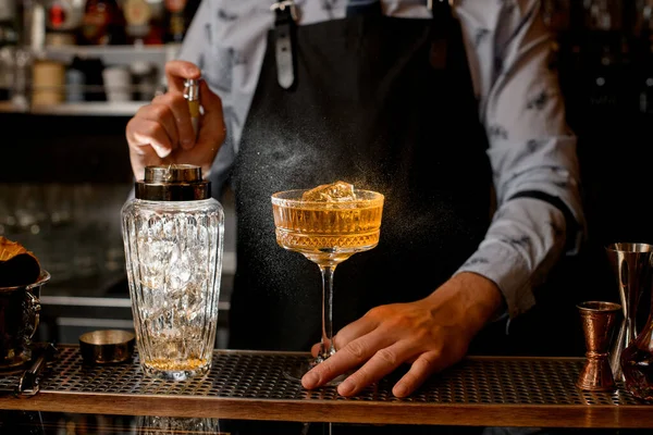 Barman energiek spuiten op koude bruine alcoholische drank op bar teller. — Stockfoto