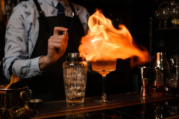 Professional bartender spray and burn cold brown alcoholic drink on bar counter. — Stock Photo, Image