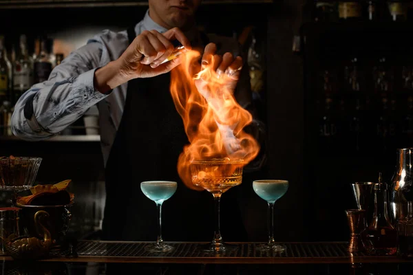 Barkeeper sprüht und verbrennt alkoholisches Getränk im Weinglas. — Stockfoto