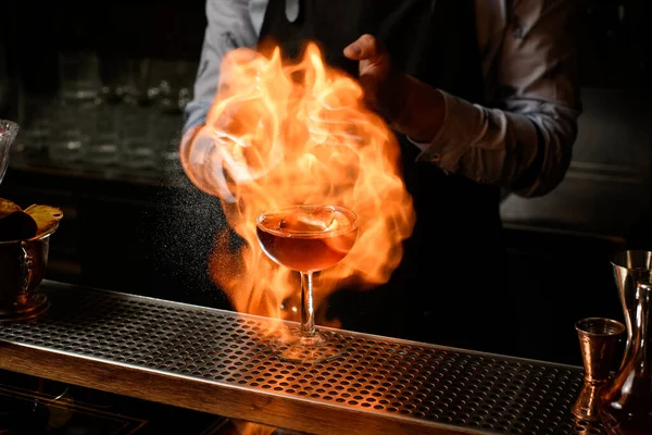Wineglass with alcoholic drink in fire stands on bar counter. — Stock Photo, Image
