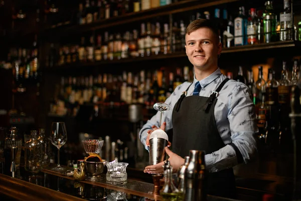 Profesionální mladý usměvavý barman připravuje sklo a třepačka, aby koktejl. — Stock fotografie