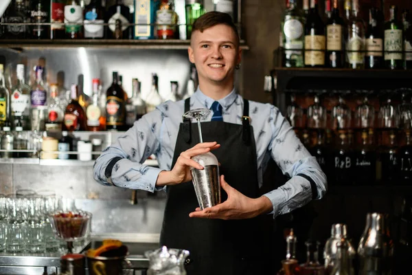 Ung leende bartender förbereda glas och shaker för att göra cocktail. — Stockfoto