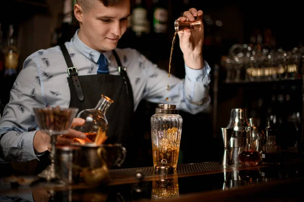Camarero joven en el bar vierte beber en la coctelera utilizando vaso de precipitados — Foto de Stock