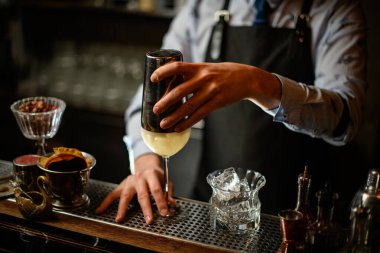 Barmen bardağı bardağın üstünde kokteyl ile tutuyor..