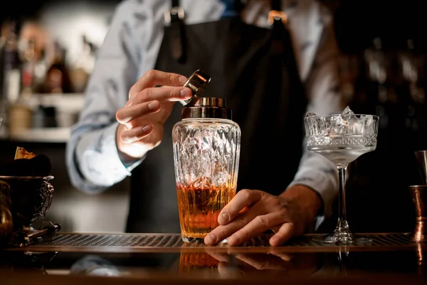 Close-up glazen shaker met bruine alcoholische drank en ijs. — Stockfoto