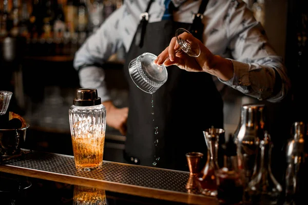 man at bar prepares glass for cocktail.