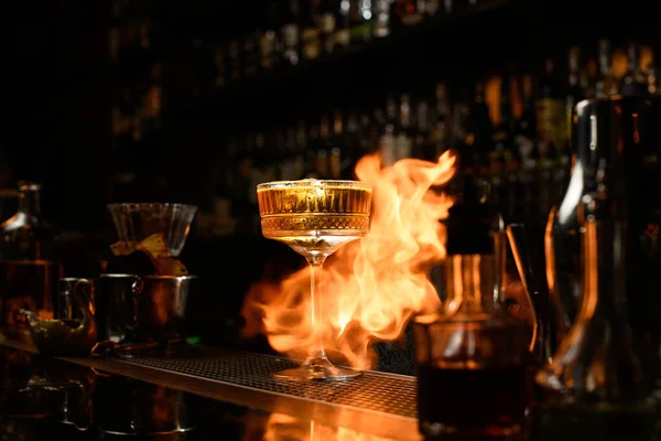 Vedere frumoasă a sticlei cu cocktail pe standuri de incendiu la contorul de bar . — Fotografie, imagine de stoc