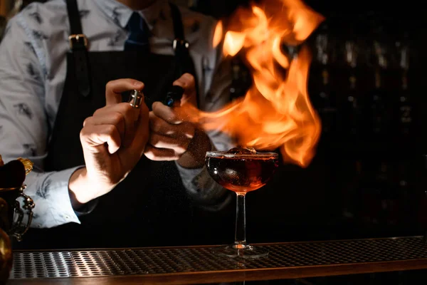 Бармен разжигает огонь над стеклом с коктейлем — стоковое фото