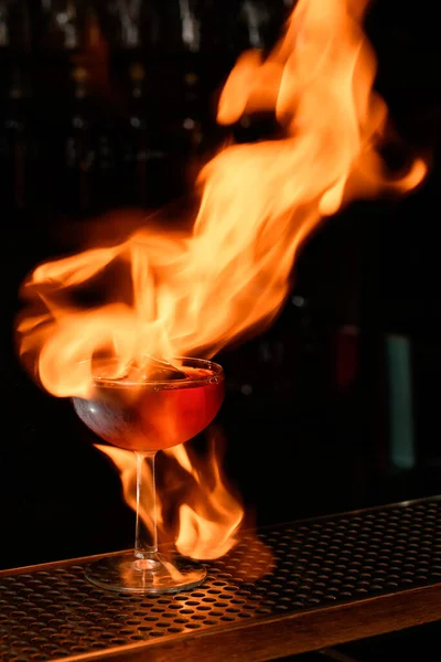 Close-up of glass with cocktail on fire stands at bar counter. — Stock Photo, Image