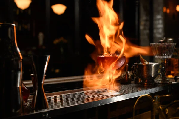 Sklo s koktejlem na ohni stojí u pultu baru. — Stock fotografie