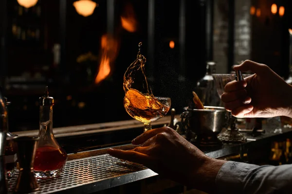 Barkeeper hält mit der Hand Glas mit verspritztem Alkohol und sprüht darauf. — Stockfoto