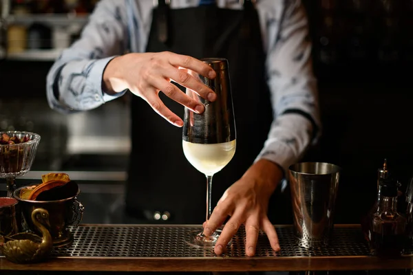 Siyah önlüklü barmen bardağın üzerinde kokteyl tutuyor.. — Stok fotoğraf