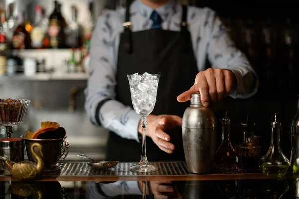 Склянка льоду, різні пляшки алкогольних напоїв та шейкер стоять у барі . — стокове фото