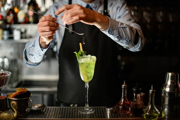 Barman pečlivě zdobí prášek ledově zelený koktejl ve skle. — Stock fotografie