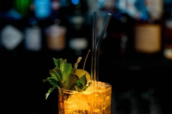 Primo piano. Bicchiere di bevanda ghiacciata decorato da foglie di menta, bacche e bastoncini di vetro . — Foto Stock