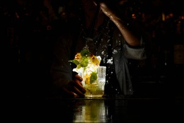Koyu bardaki kadın enerji dolu bir şekilde limon ve buz dilimleriyle ezilmiş..