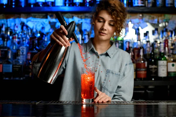 Young bartender woman accurate pouring cocktail using steel siphon — Stock Photo, Image