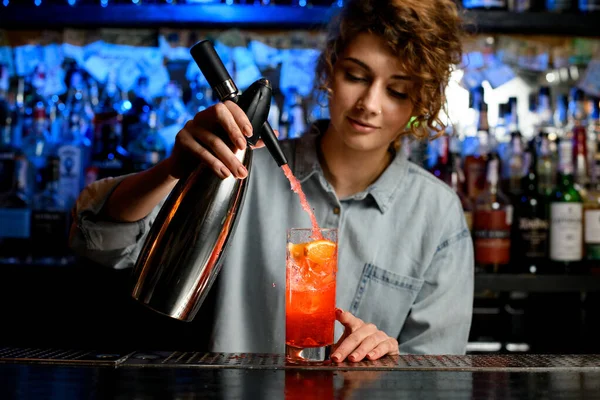 Jovem bartender mulher cuidadosamente derramando coquetel usando sifão de aço — Fotografia de Stock