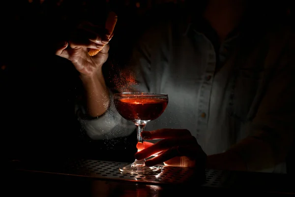 Kobieta barman delikatnie posypuje sok cytrusowy na kieliszku do wina koktajlem w barze — Zdjęcie stockowe