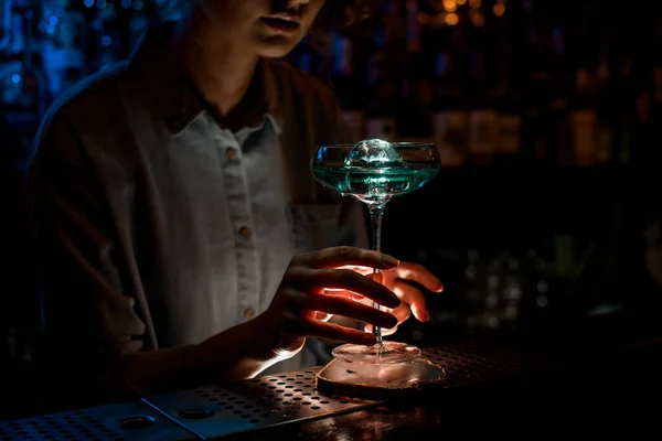 Леди в темном баре держит красивый стакан синего коктейля . — стоковое фото