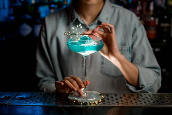 Een close-up. Lady barman versiert glas met cocktail bloem tak — Stockfoto