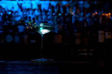 Barın üzerinde güzel mavi kokteyl standı olan cam..