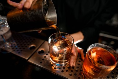 Yakın plan barmen negroni kokteylini barın tezgahına ustaca koyar..