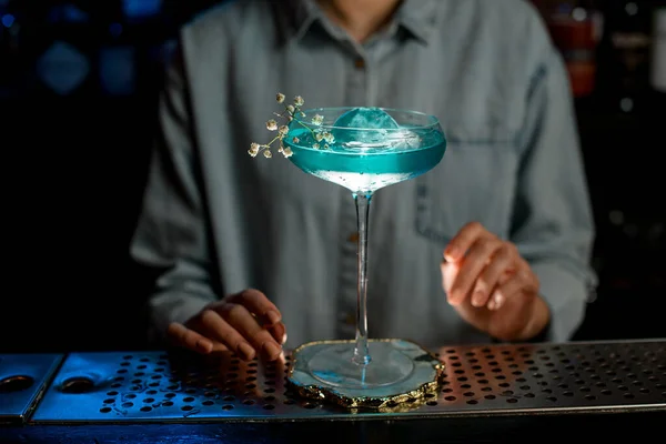 Närbild. Glas med blå dryck dekorerad blomma gren stå på bar. — Stockfoto